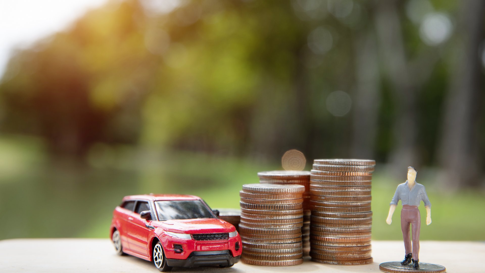 Model SUV and stack of coins symbolising economical and efficient car choices.