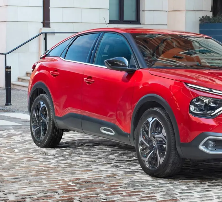 Red Citroën C4 parked on a cobbled street, showcasing its sleek design and modern exterior styling.