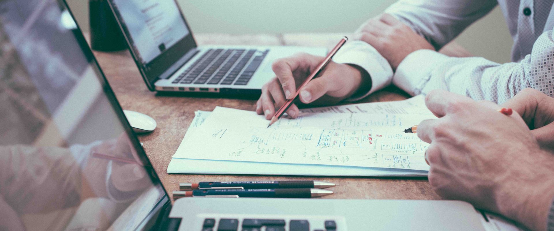 Two people reviewing car depreciation data and charts next to laptops on a wooden desk