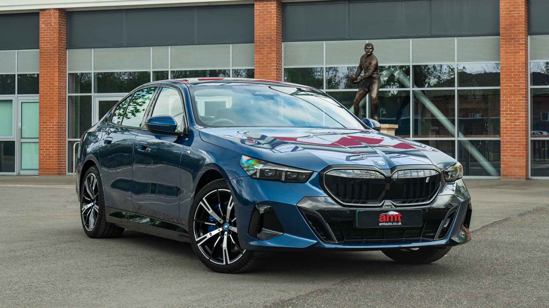 BMW i5 saloon parked outside modern offices, featured on AMT Auto's BMW lease deals page.