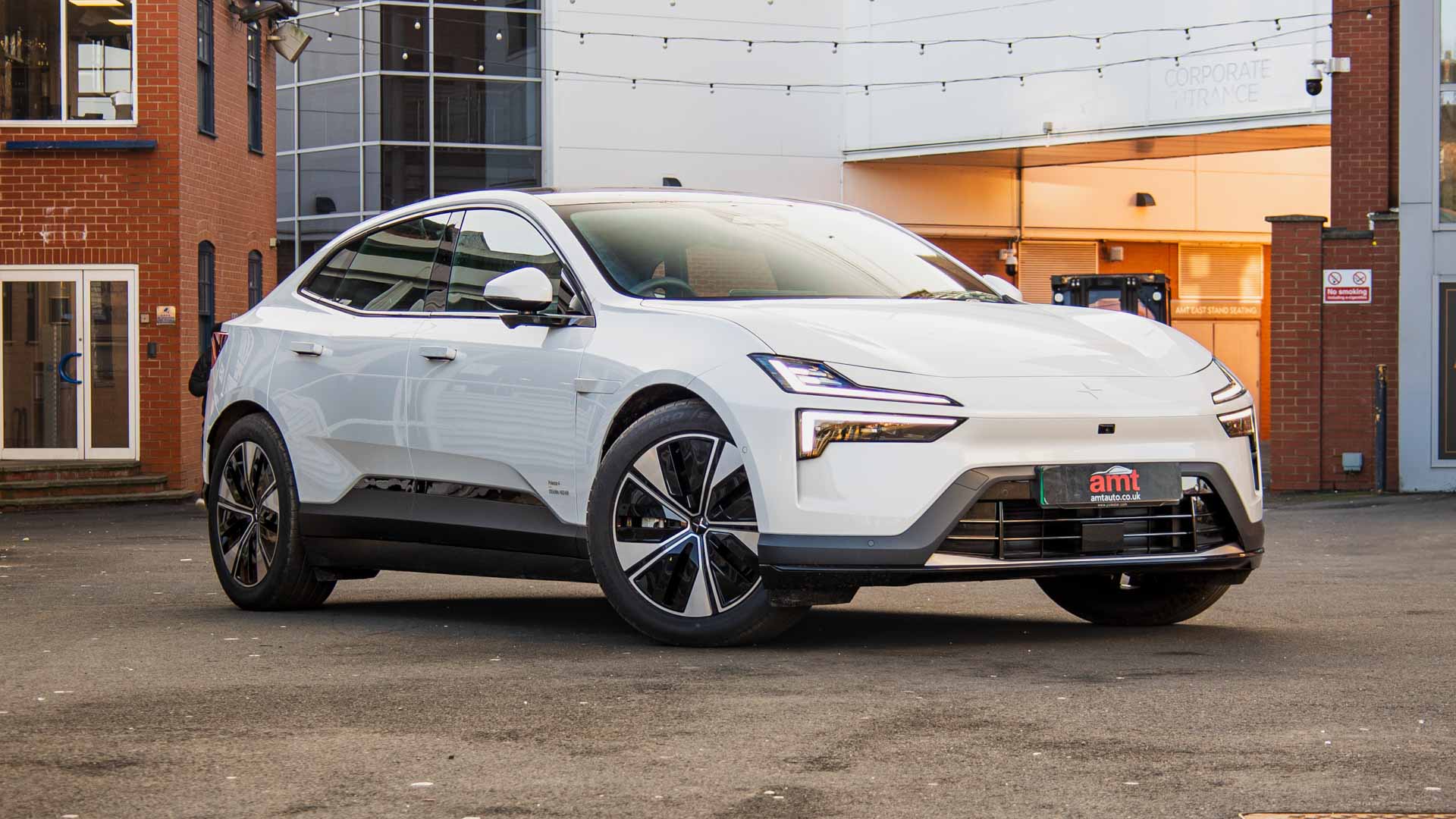 White Polestar electric lease car parked outside AMT Auto, showcasing its sculpted front end and aerodynamic side profile.