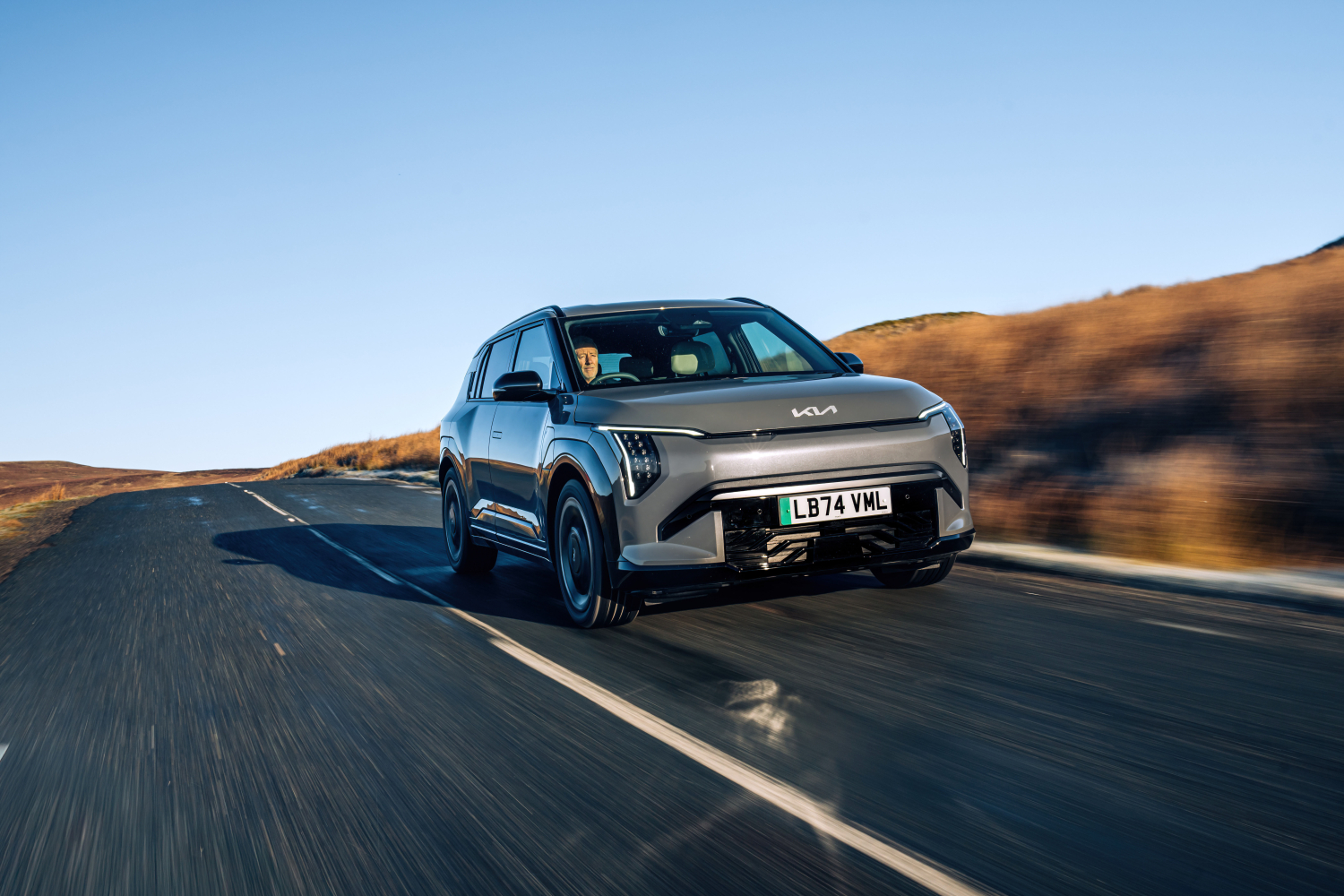 Kia EV3 driving down a country road.