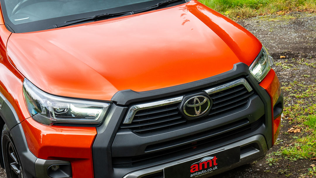 Close-up of an orange Toyota Hilux grille and front end, representing pick-up leasing options.