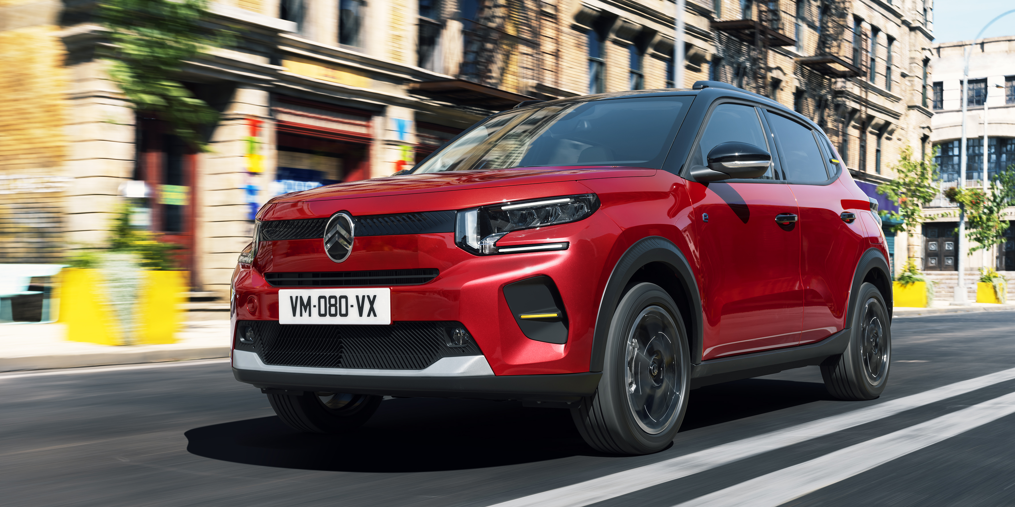 The new Citroen e-C3 driving through a city setting.