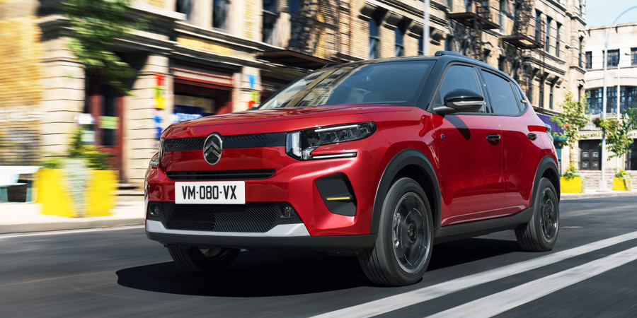 The new Citroen e-C3 driving through a city setting.