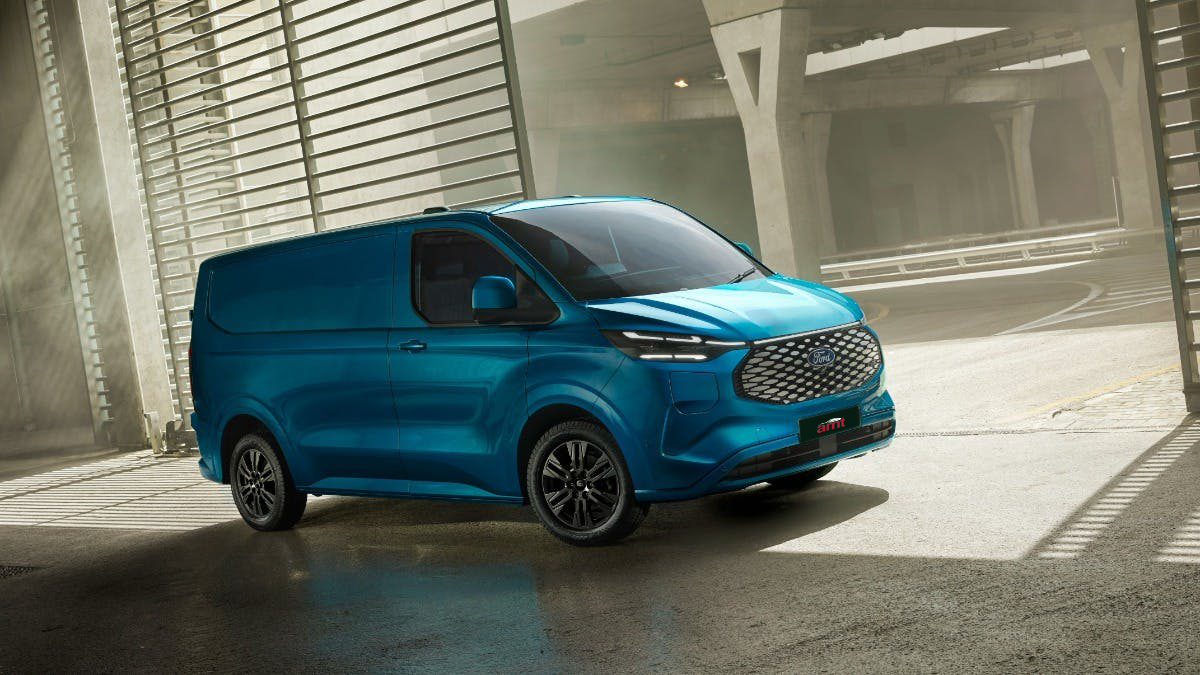 Blue Ford E-Transit Custom van parked in a modern urban environment with sunlight casting shadows across the ground.