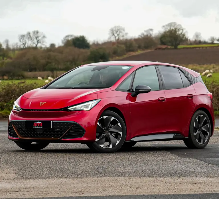 Red Cupra Born electric car parked at a rural junction, shown as a business Cupra leasing options available from AMT Auto.