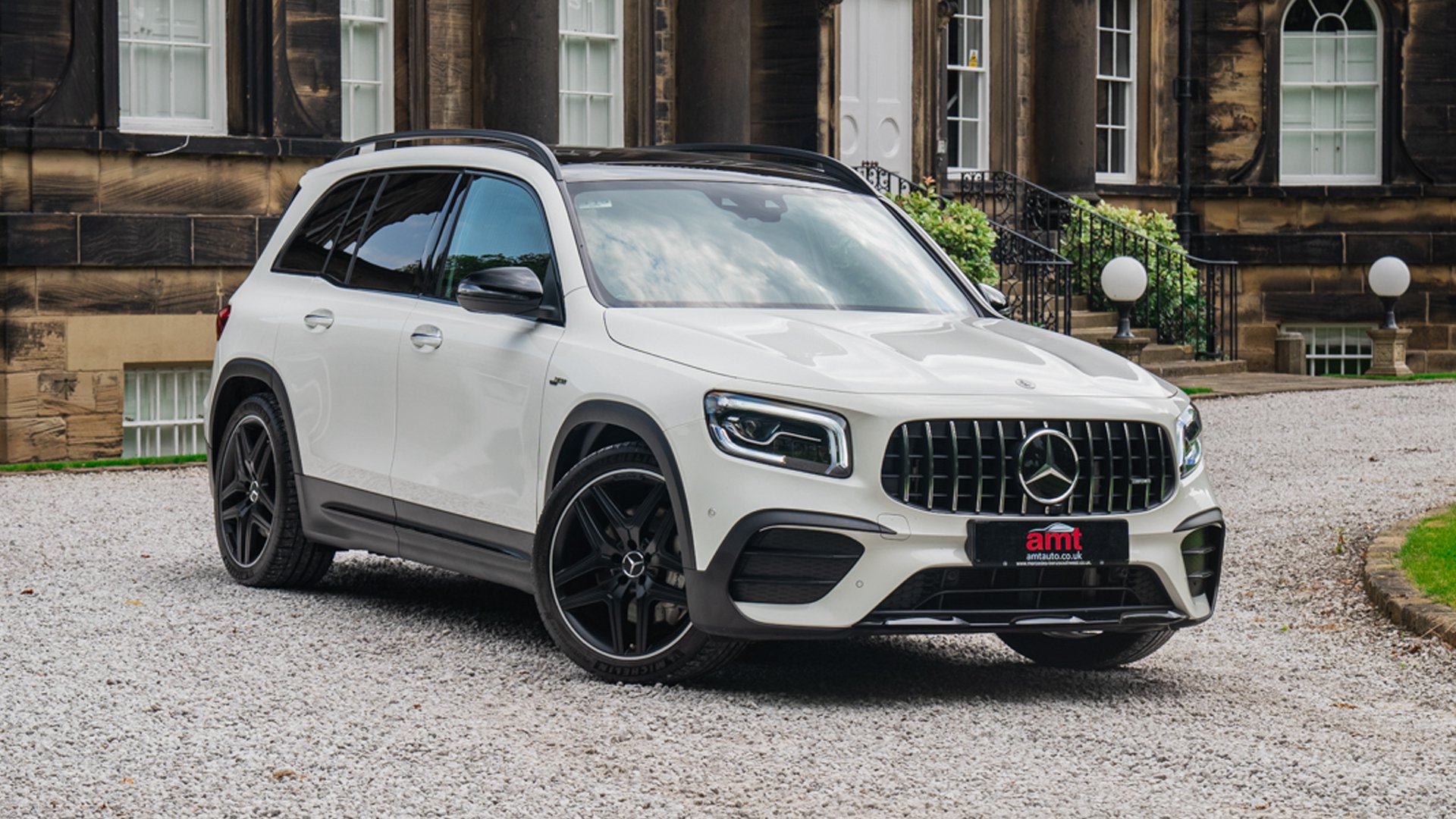 White 2021 Mercedes-Benz GLB35 Premium Plus parked outside a grand building in AMT Auto’s leasing review.