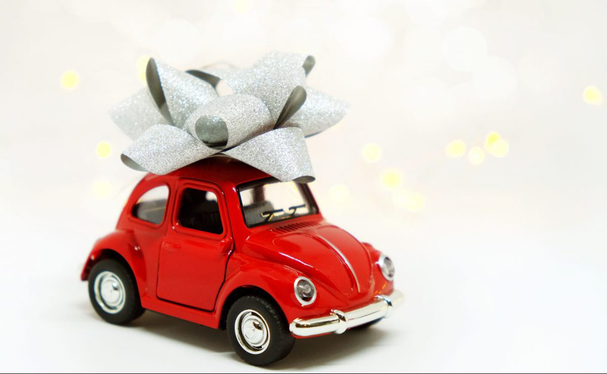 Toy red car with a large silver bow on the roof, symbolising a gift for a new driver.