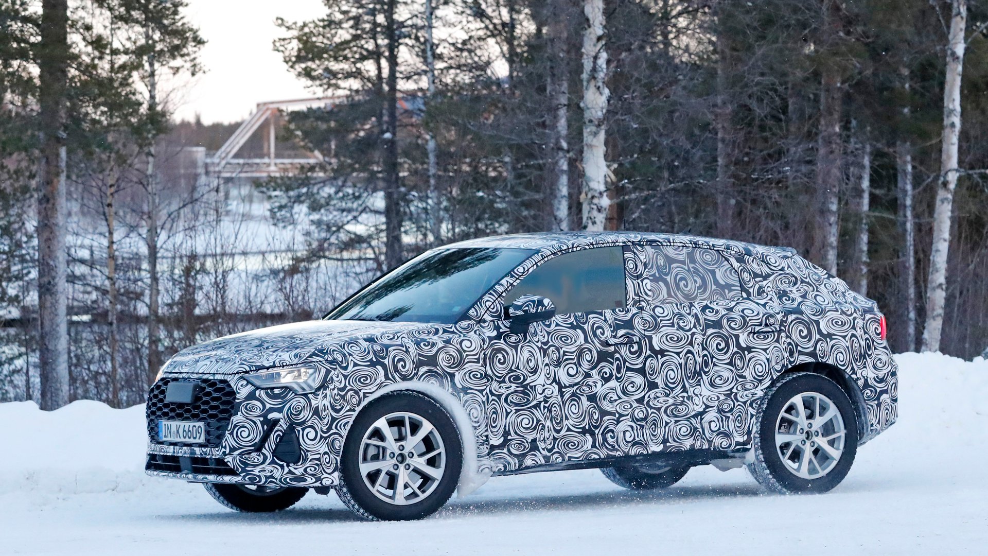 Heavily camouflaged prototype SUV undergoing winter testing in snowy conditions, hinting at new car models expected in 2019.