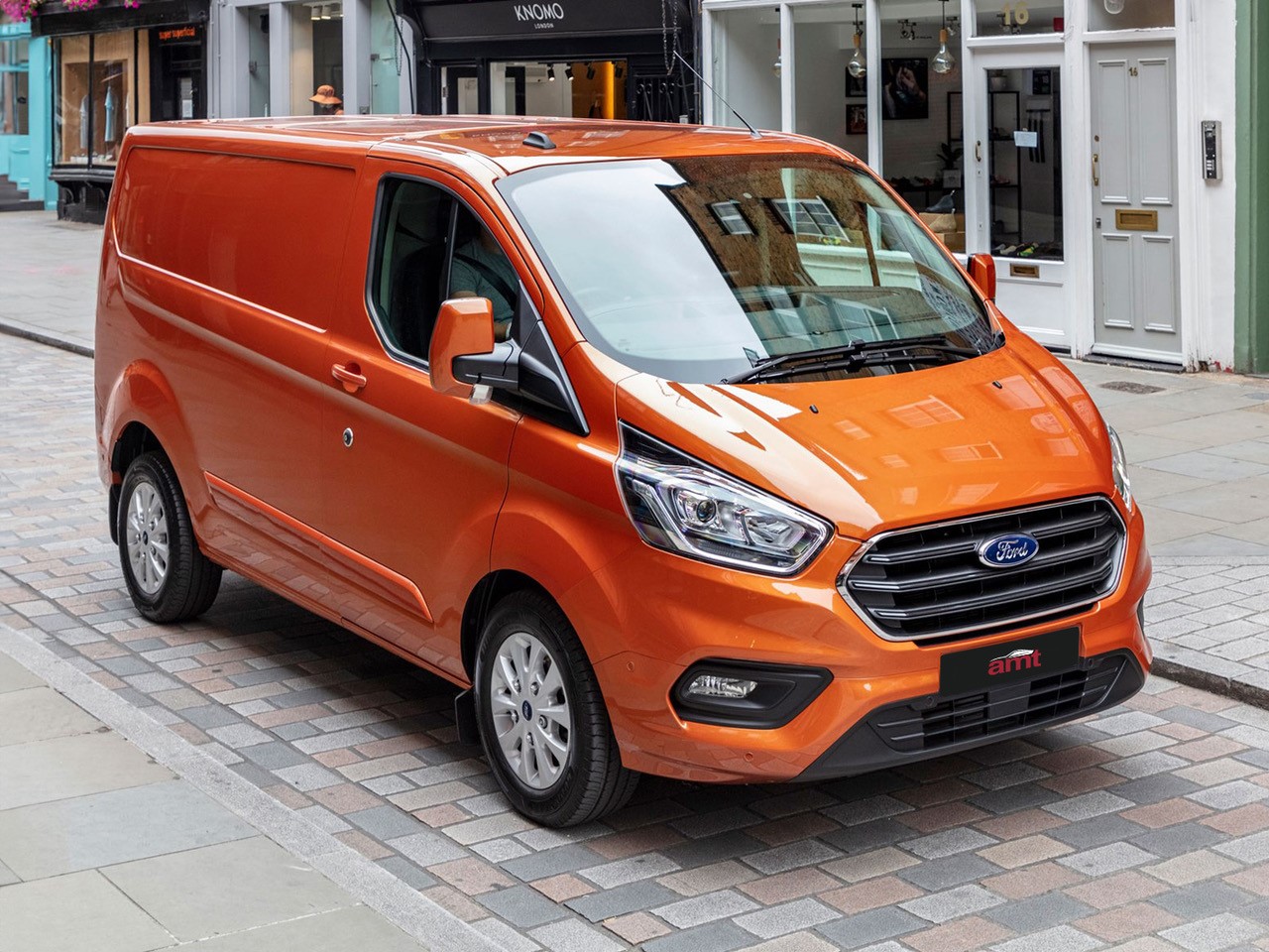 Ford Transit Custom in bright orange parked on a city street, featured in AMT’s best vans to lease.