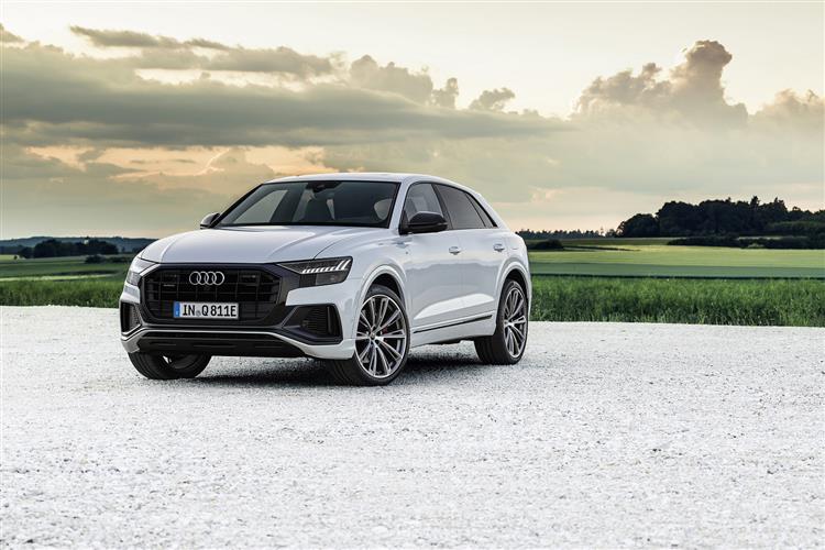 Picture of a white audi car on white gravel with a green field in the background