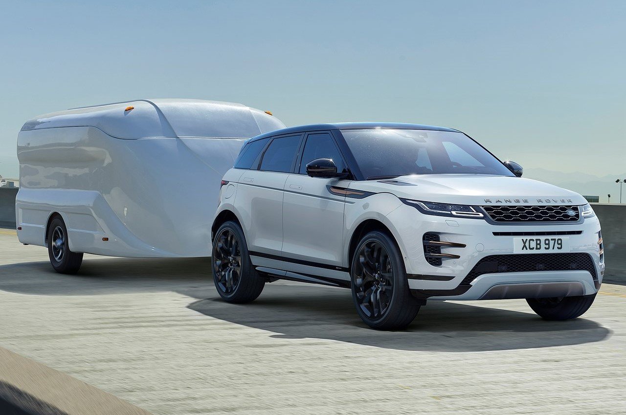 Range Rover Evoque towing modern trailer on open road, showcasing SUV’s towing ability and sleek design.