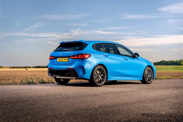A blue BMW 1 Series car on a road with a field in the background on a sunny day