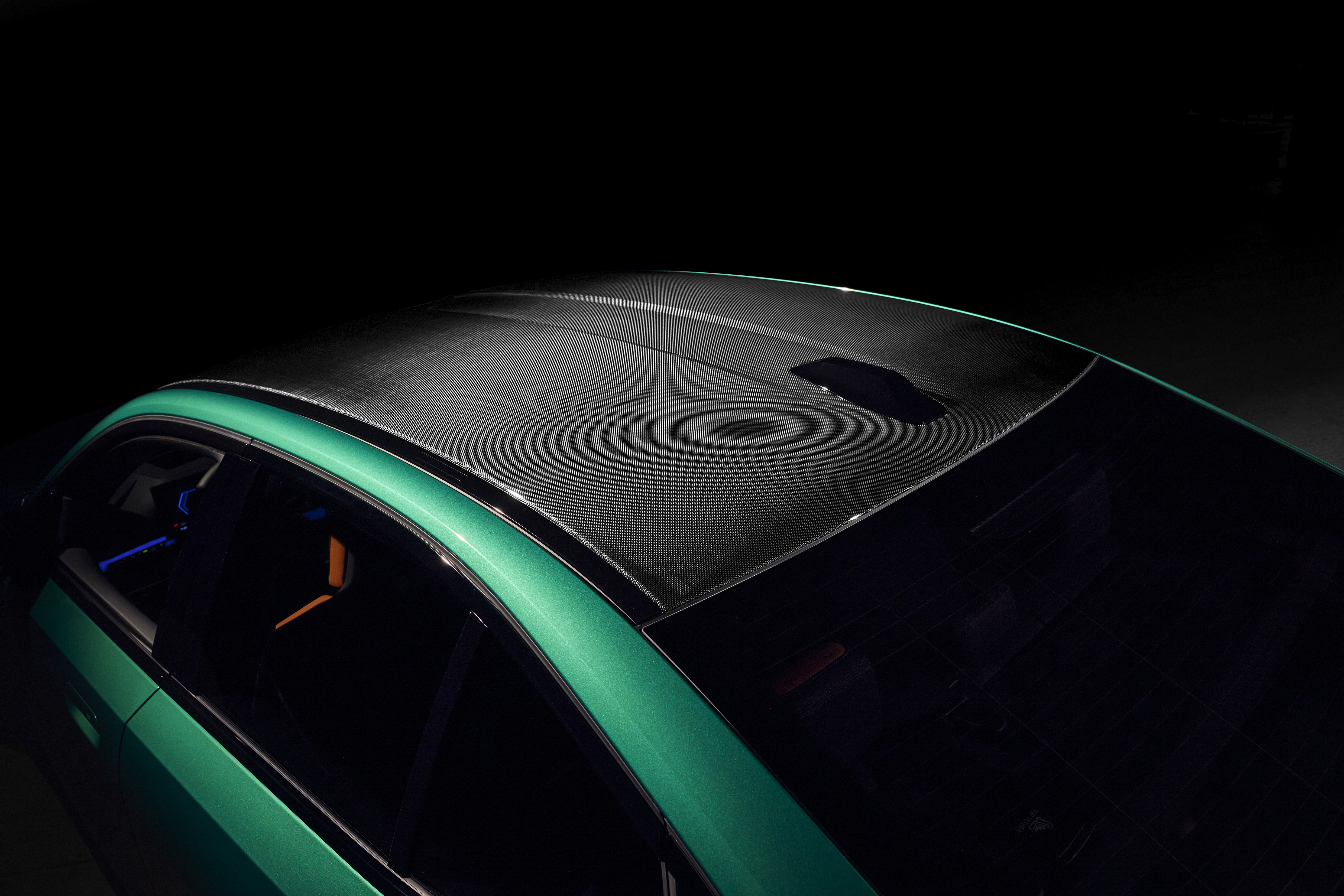 Close-up photograph of a black carbon edition roof, featuring glossy carbon fiber weave texture under natural light.