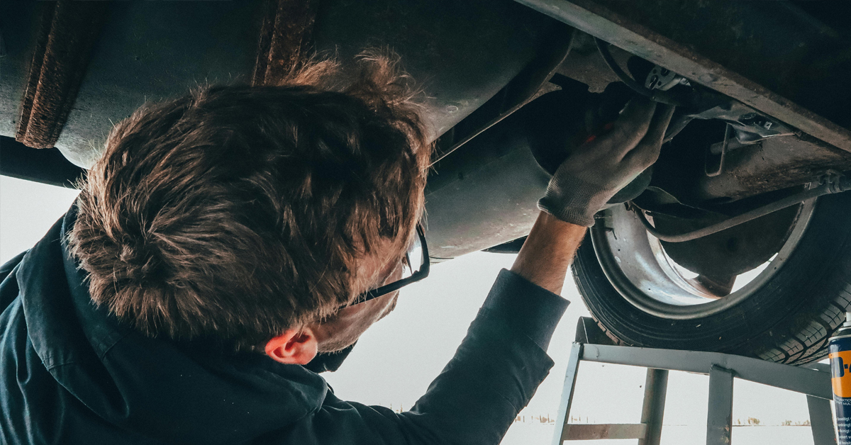 An image of a man working underneath a car
