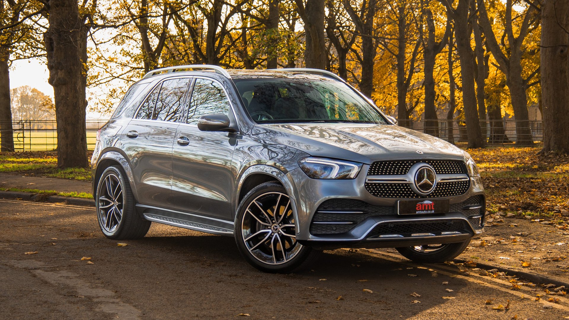 Silver Mercedes-Benz GLE SUV parked on a leaf-covered road in autumn.